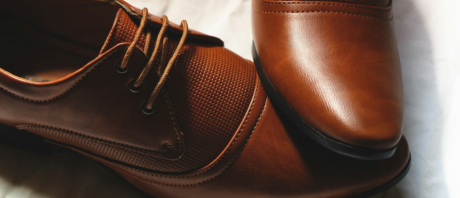 Deux chaussures en cuir camel posées sur un drap blanc