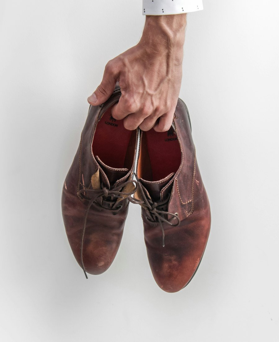 Une main tient une paire de chaussures en cuir